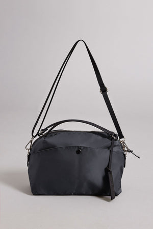 The NYLON CROSSBODY BAG by Velvet by Graham & Spencer is a black rectangular nylon shoulder bag with a front pocket, top zipper, adjustable strap, and small tag—perfect for everyday use and shown against a neutral background.