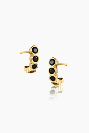 ASTRID BLACK HOOP EARRINGS BY THATCH feature three black circular stones each.