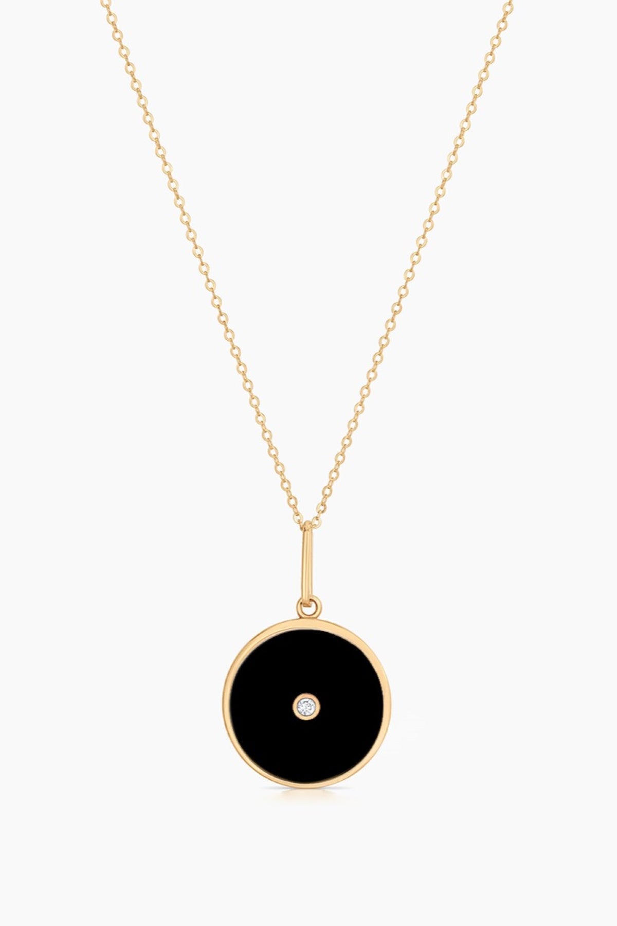 The BALIA BLACK ENAMEL NECKLACE BY THATCH from Thatch features a gold chain and a round black pendant with a small central diamond.-38571115118785