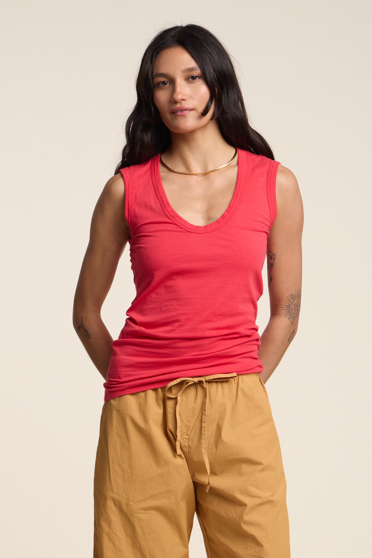 A woman wearing the ESTINA TANK TOP by Velvet by Graham & Spencer in red and light brown drawstring pants stands against a plain, light background.-41371910701249