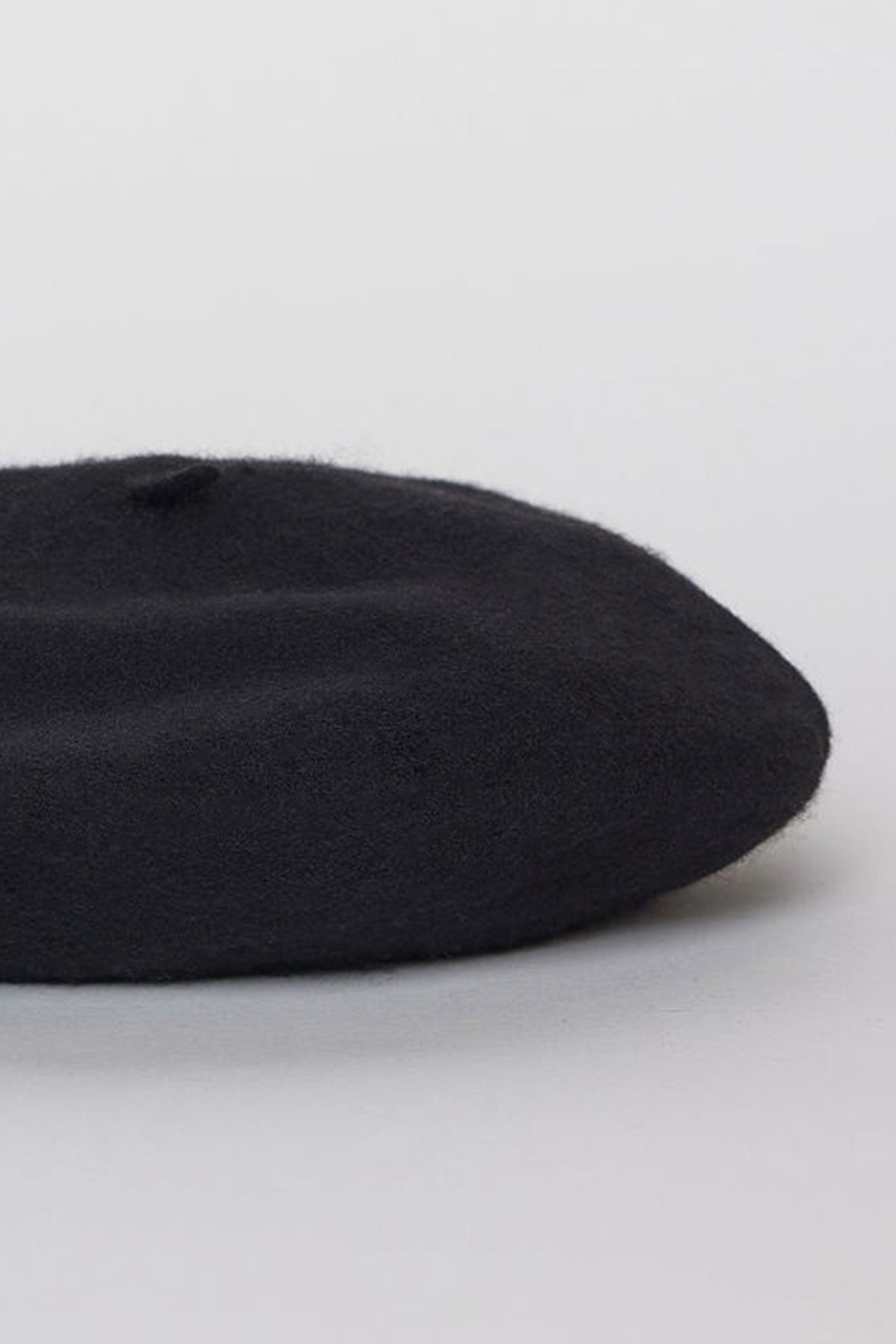 A CLASSIC BERET by Velvet by Graham & Spencer is placed on a light gray surface.