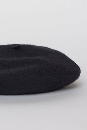 A CLASSIC BERET by Velvet by Graham & Spencer is placed on a light gray surface.