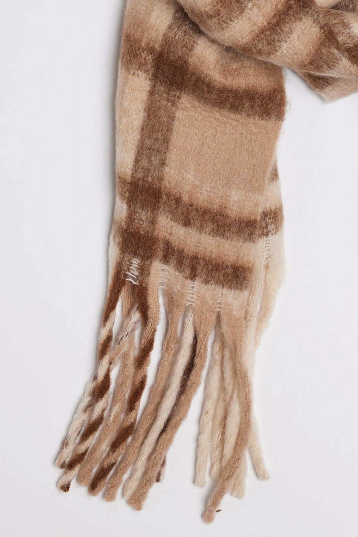 A close-up of the COZY PLAID SCARF from Velvet by Graham & Spencer, showcasing its beige and brown plaid pattern with fringed ends.-37930439966913