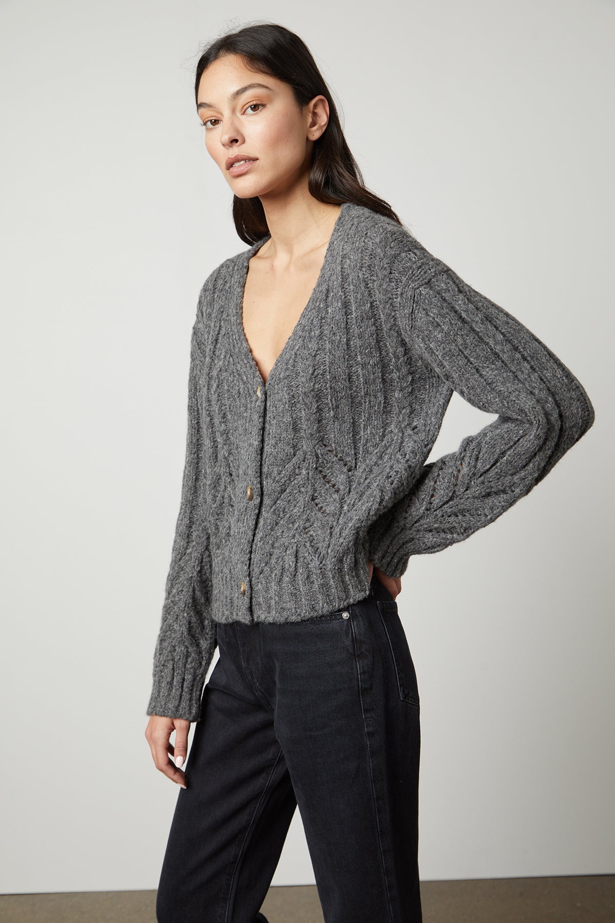 The model is wearing a HAZEL ALPACA cable knit cardigan by Velvet by Graham & Spencer with pointelle detailing.