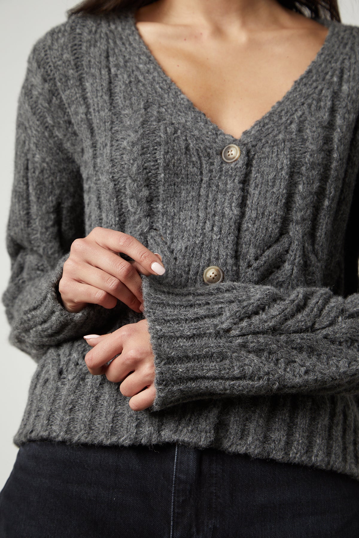 A woman wearing a Hazel Alpaca cable knit cardigan by Velvet by Graham & Spencer featuring pointelle detailing.