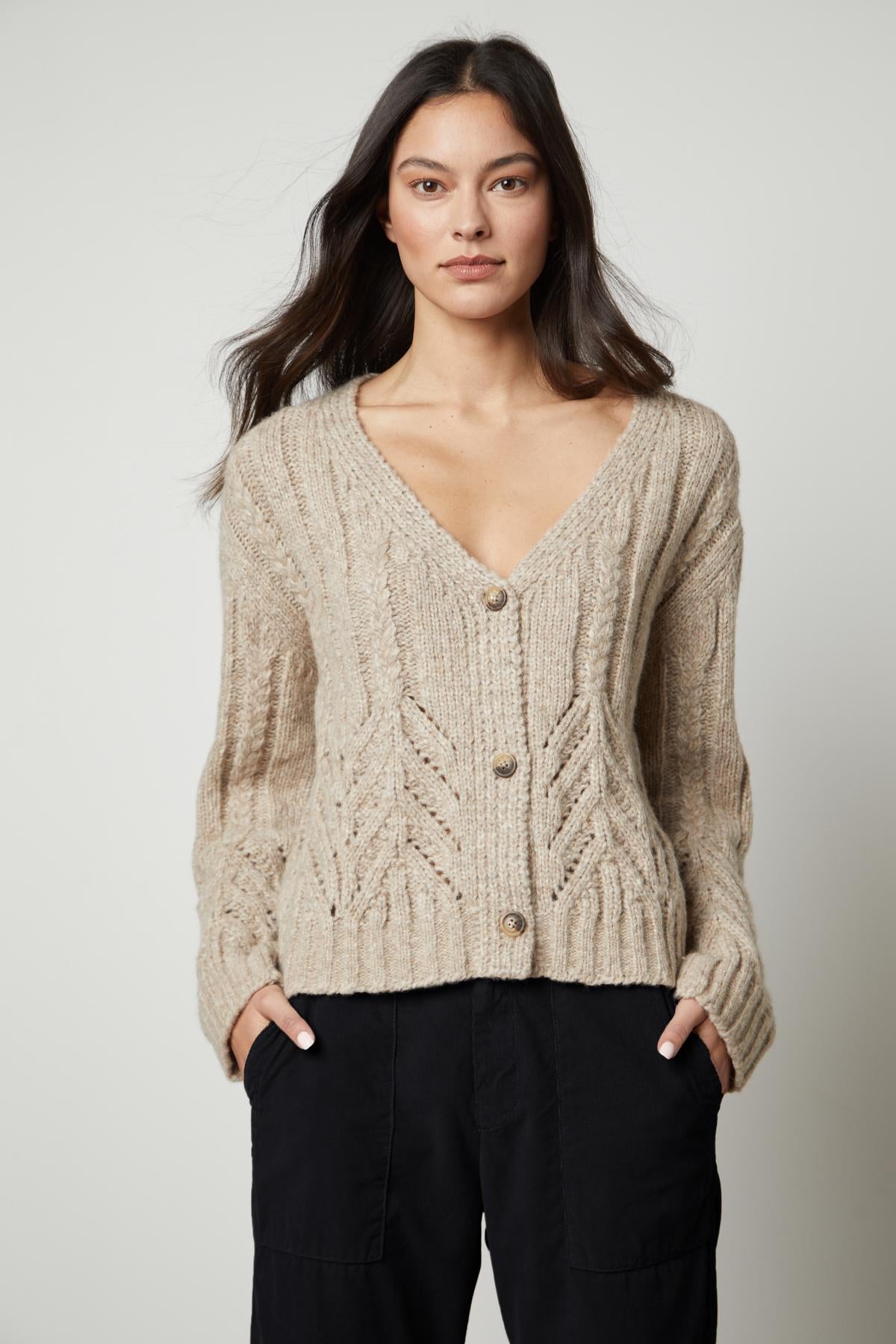 A woman wearing a Velvet by Graham & Spencer HAZEL ALPACA CABLE KNIT CARDIGAN and black pants.