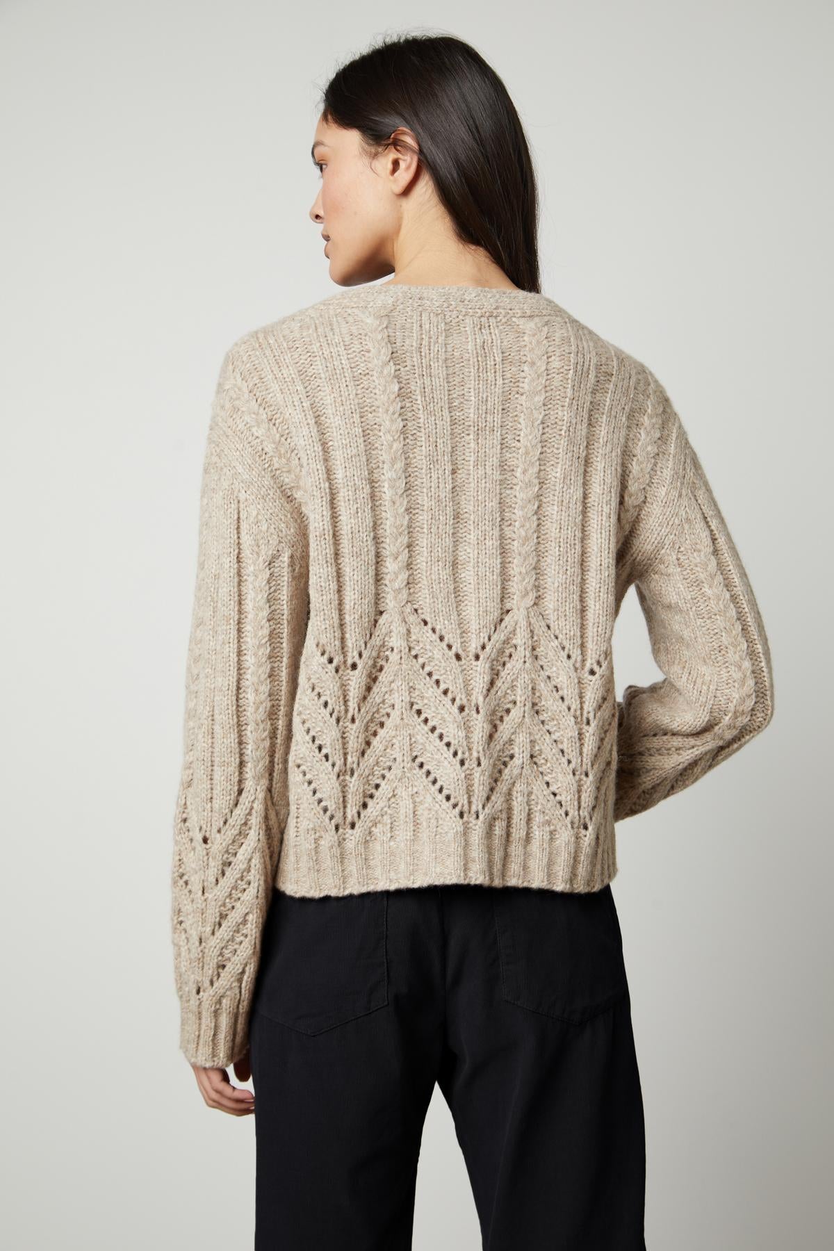 The back view of a woman wearing a Velvet by Graham & Spencer HAZEL ALPACA CABLE KNIT CARDIGAN sweater.