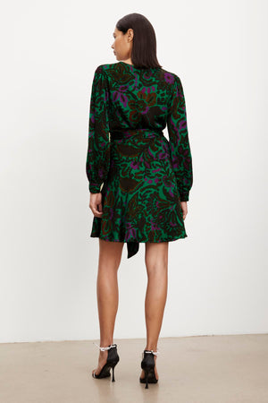 The back view of a woman wearing a Velvet by Graham & Spencer BRIDGET PRINTED SATIN WRAP DRESS with an adjustable tie waist.