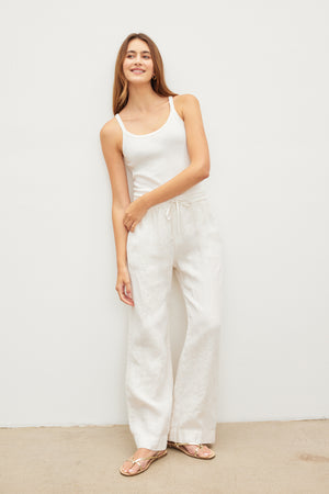 A woman wearing Velvet by Graham & Spencer's GWYNETH HEAVY LINEN PANT and a relaxed drape white tank top.