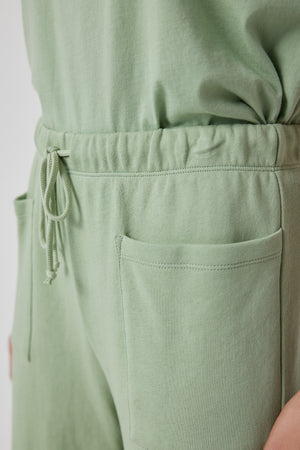 A woman is wearing a Velvet by Jenny Graham WESTLAKE SWEATPANT in green with pockets.