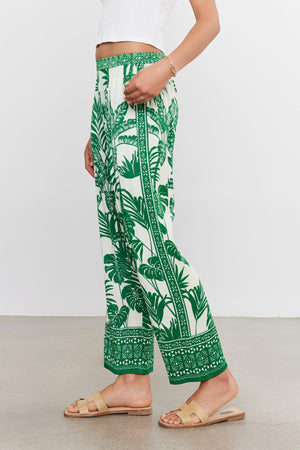 Woman wearing Velvet by Graham & Spencer's IRIS PANT with an elastic waist, paired with beige sandals, standing against a plain background.