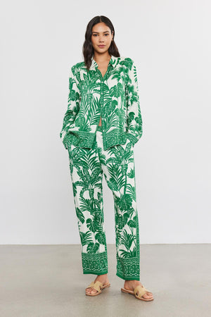 Woman in a green and white palm print suit with an elastic waist, standing in a studio wearing the IRIS PANT by Velvet by Graham & Spencer.