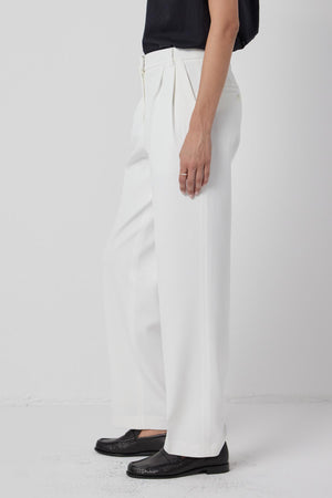 A woman wearing white Bundy Pants and a black top, wardrobe staple by Velvet by Jenny Graham.
