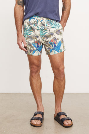 Man wearing Velvet by Graham & Spencer RICARDO SWIM SHORT and black sandals, standing against a plain background, visible from the waist down.