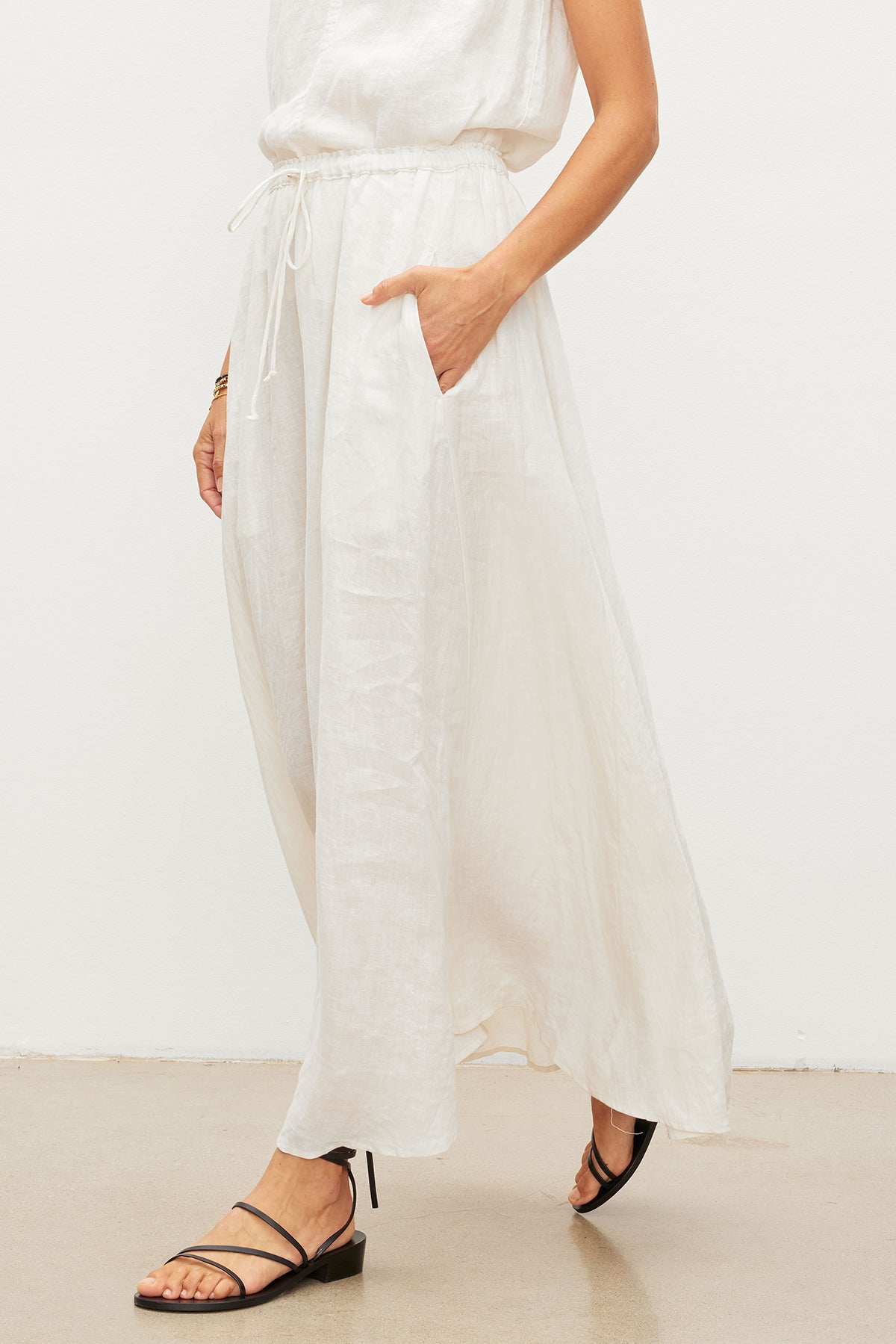 A woman wearing a Velvet by Graham & Spencer BAILEY LINEN MAXI SKIRT and sandals.-35955424264385