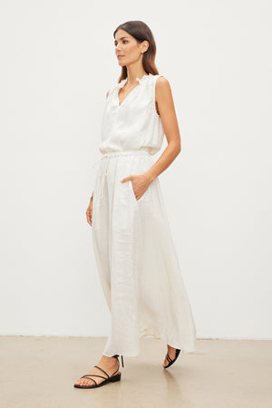 The model is wearing a white MASIE LINEN TANK TOP dress and Velvet by Graham & Spencer sandals.