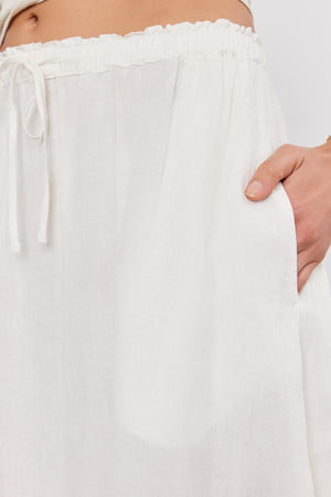 Close-up of a person's hand adjusting an elastic waist on Velvet by Graham & Spencer NEMY LINEN SKIRT.
