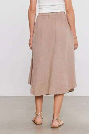 Woman in a white sleeveless top and beige NEMY LINEN SKIRT with an elastic waist, viewed from behind, standing against a plain background. (Brand: Velvet by Graham & Spencer)