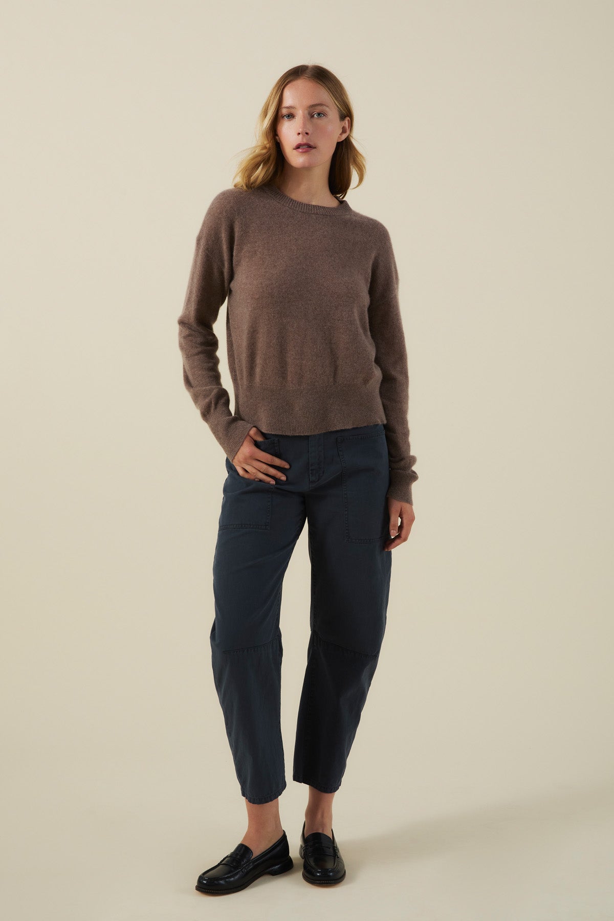 Woman wearing an ALBA CASHMERE SWEATER in brown, dark blue utility-style pants, and black loafers.-46498787164353