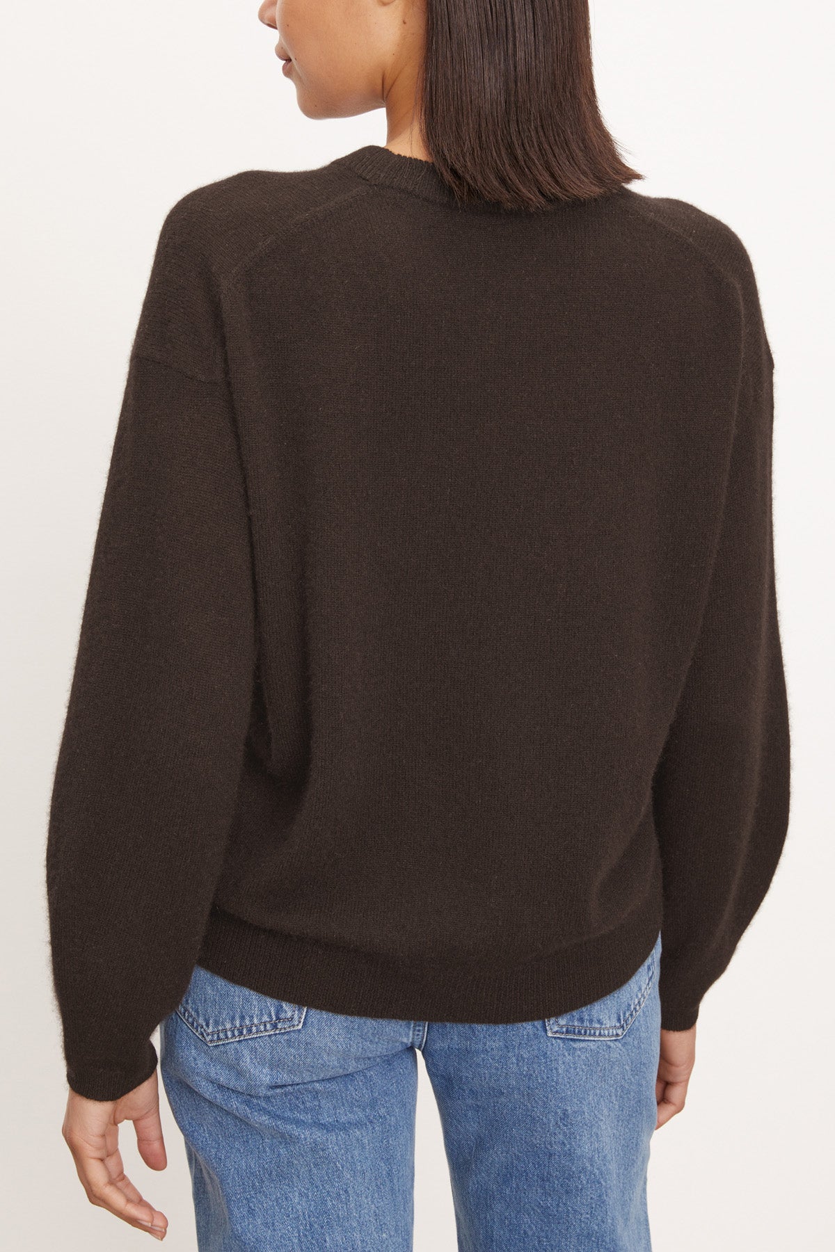 A person wears the BRYNNE CASHMERE SWEATER by Velvet by Graham & Spencer in dark brown, paired with blue jeans, shown from the back against a plain light background.-40281808928961