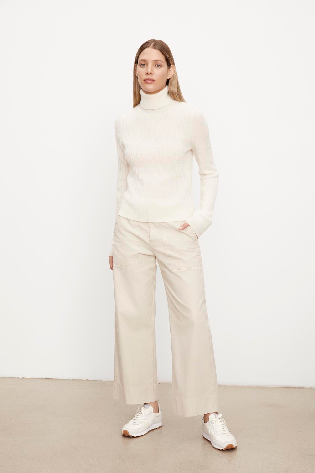 The model is wearing a Velvet by Graham & Spencer Lori Cashmere turtleneck sweater and wide leg trousers.