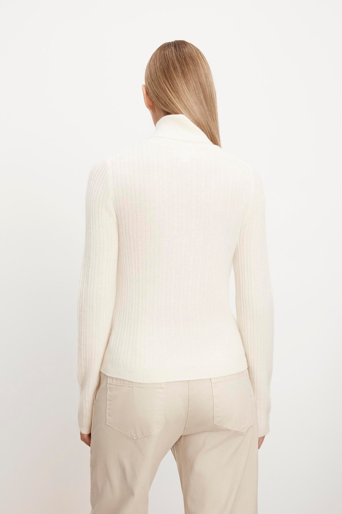 The view of a woman wearing a Velvet by Graham & Spencer LORI CASHMERE TURTLENECK SWEATER.-35727549202625