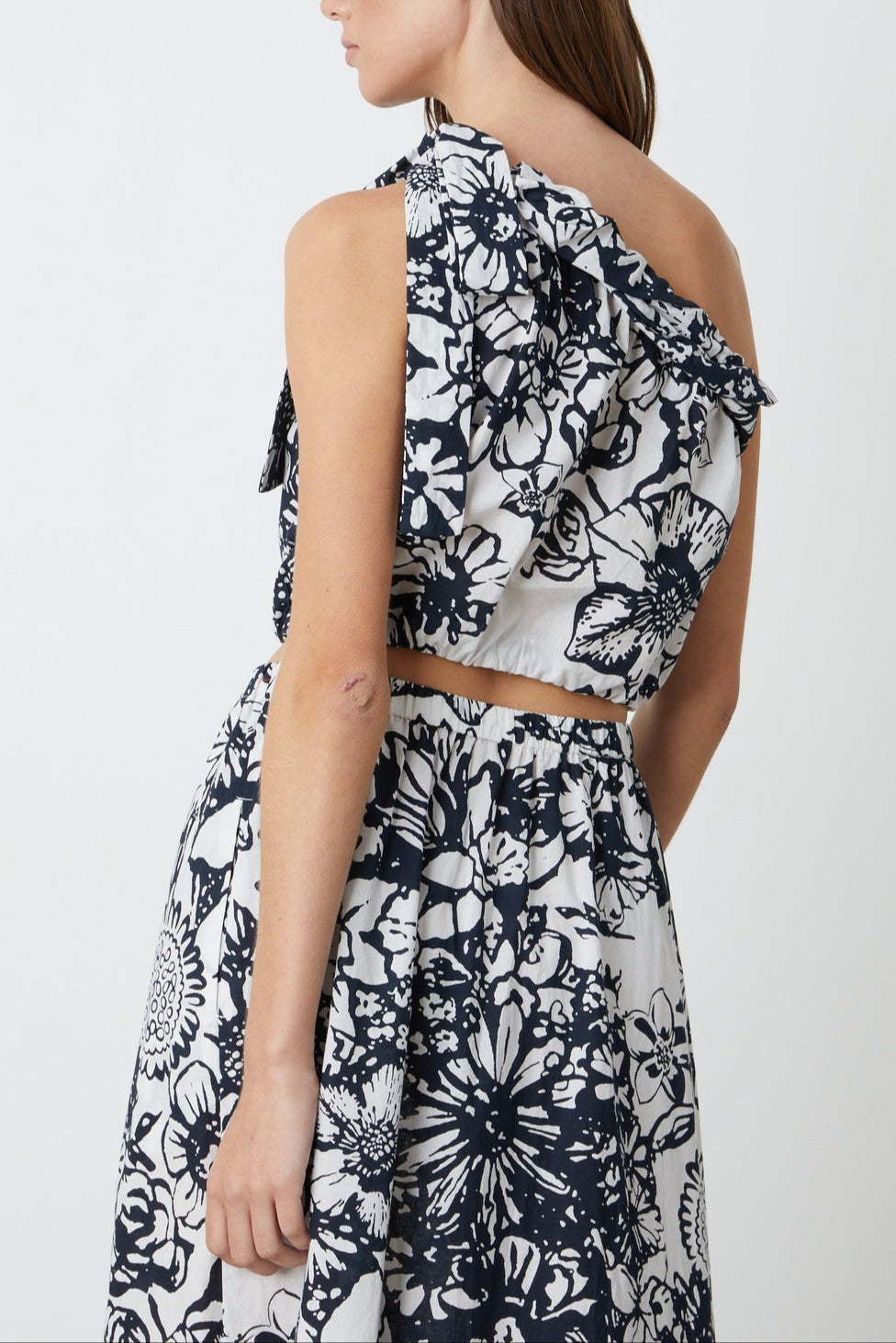 The back view of a woman in a Velvet by Graham & Spencer CAMILLA PRINTED ONE SHOULDER TOP.