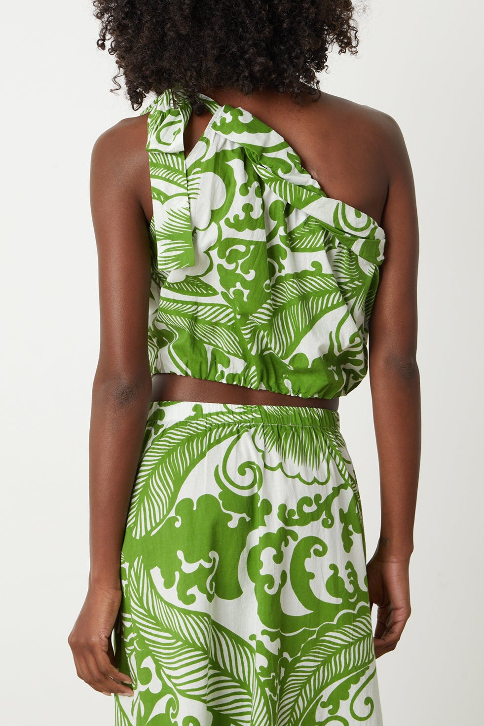the back view of a woman in a Velvet by Graham & Spencer CAMILLA PRINTED ONE SHOULDER TOP dress.