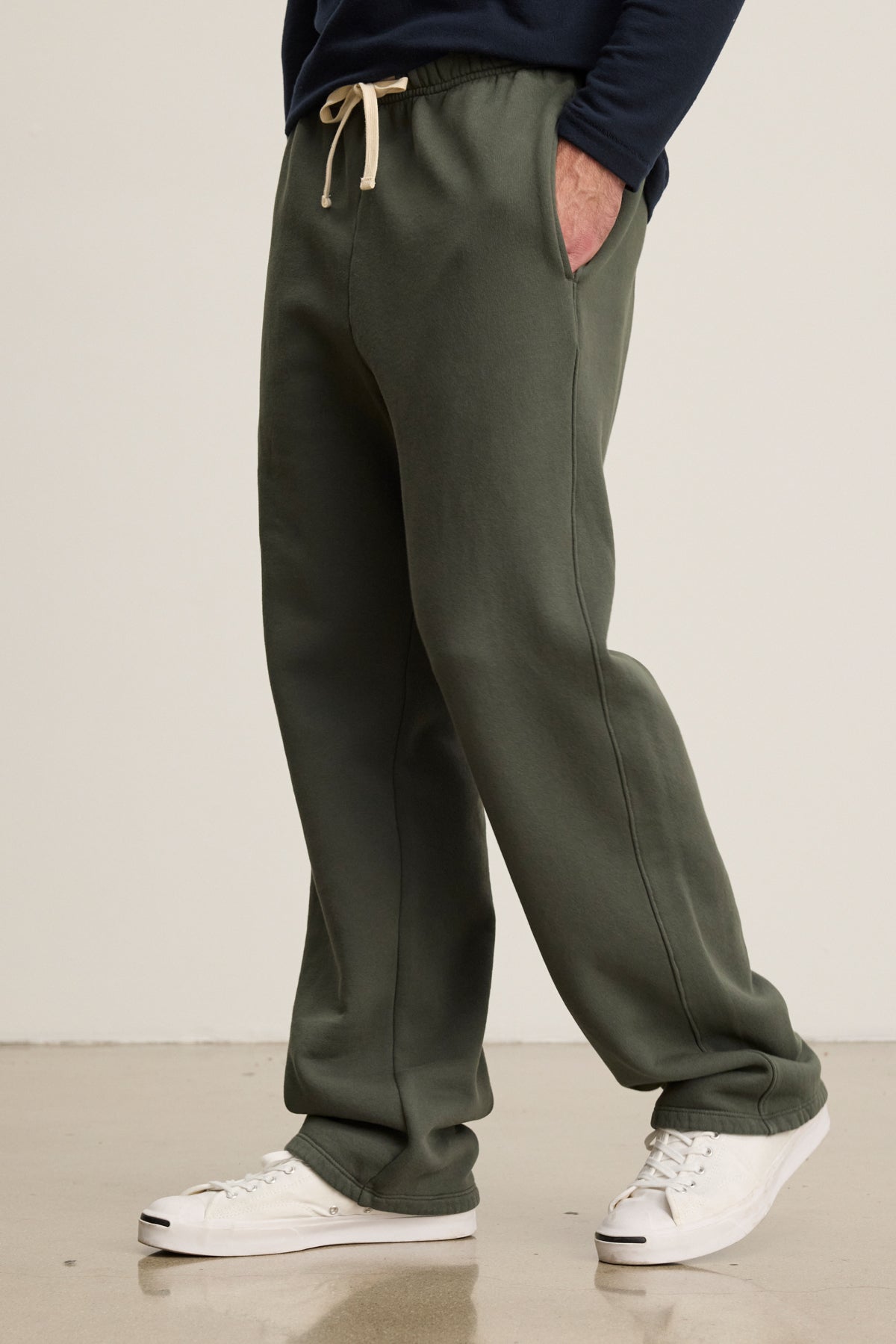 Wearing Velvet by Graham & Spencer’s HUDSON SWEATPANT in olive green cotton fleece with pockets, paired with a navy long-sleeve shirt and white sneakers, this look is perfect for everyday comfort and style.