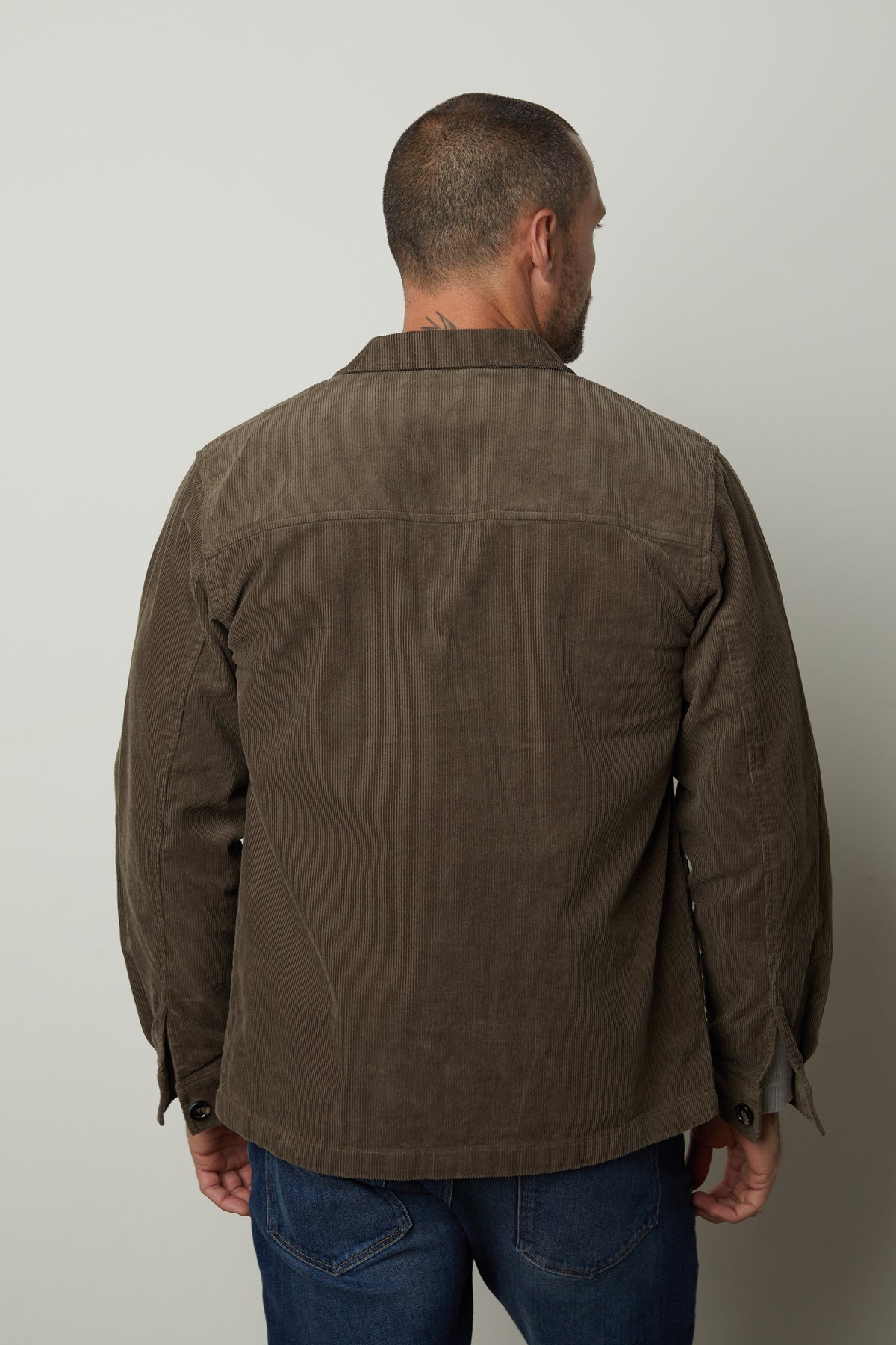 The back view of a man wearing a Velvet by Graham & Spencer REIKO CORDUROY CHORE JACKET with front patch pockets.-26846359388353