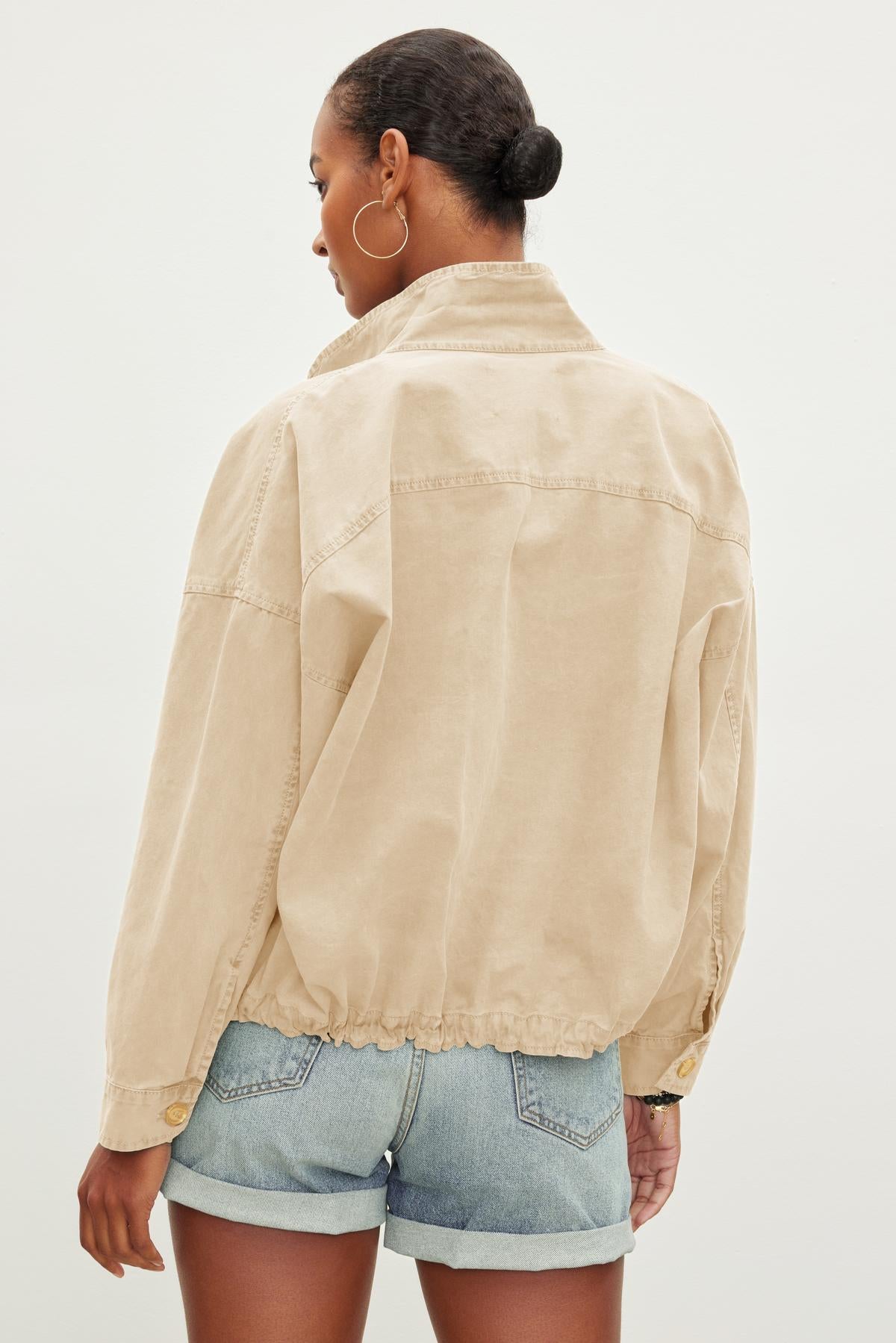 A person with short hair, wearing hoop earrings and a Velvet by Graham & Spencer NICOLA JACKET over denim shorts, stands with their back to the camera against a plain background.-37229022019777