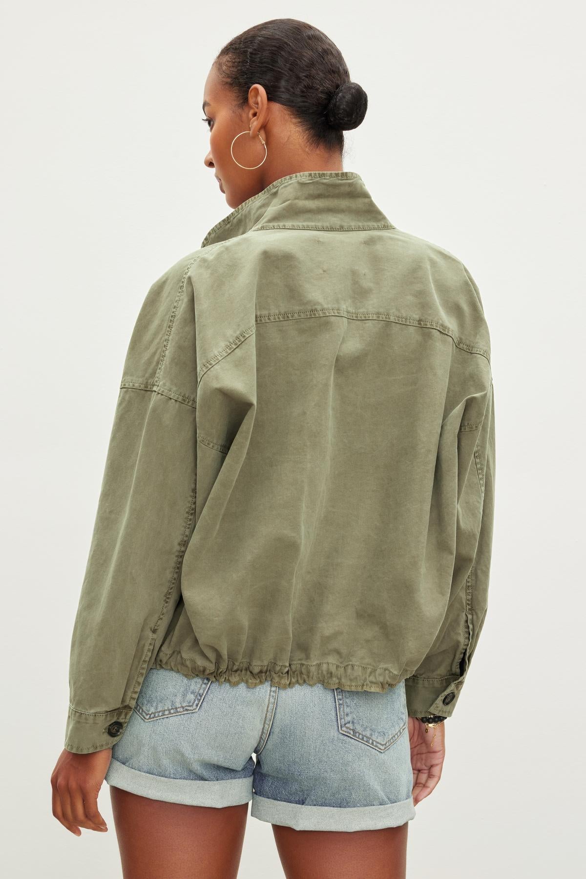 A person with short hair is wearing an olive green NICOLA JACKET by Velvet by Graham & Spencer and blue denim shorts, viewed from the back against a plain background.-37073677451457