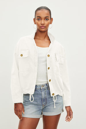 A person with short hair wears a Velvet by Graham & Spencer NICOLA JACKET over a white tank top and blue denim shorts, standing against a plain background.
