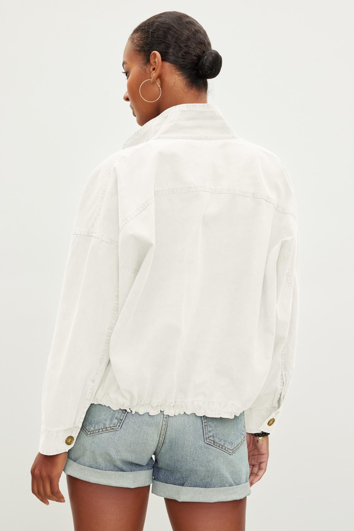 A person with short hair is seen from the back, wearing a NICOLA JACKET by Velvet by Graham & Spencer and blue denim shorts.-37229021954241