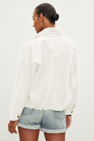 A person with short hair is seen from the back, wearing a NICOLA JACKET by Velvet by Graham & Spencer and blue denim shorts.