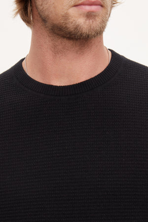 A man with long hair wearing a black Velvet by Graham & Spencer cashmere sweater.