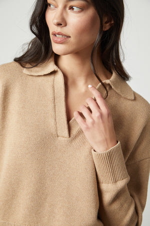 The model is wearing a layered LUCIE POLO SWEATER by Velvet by Graham & Spencer with a ribbed V-neckline.