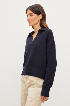 The model is wearing a Velvet by Graham & Spencer LUCIE POLO SWEATER with stripes and beige pants.