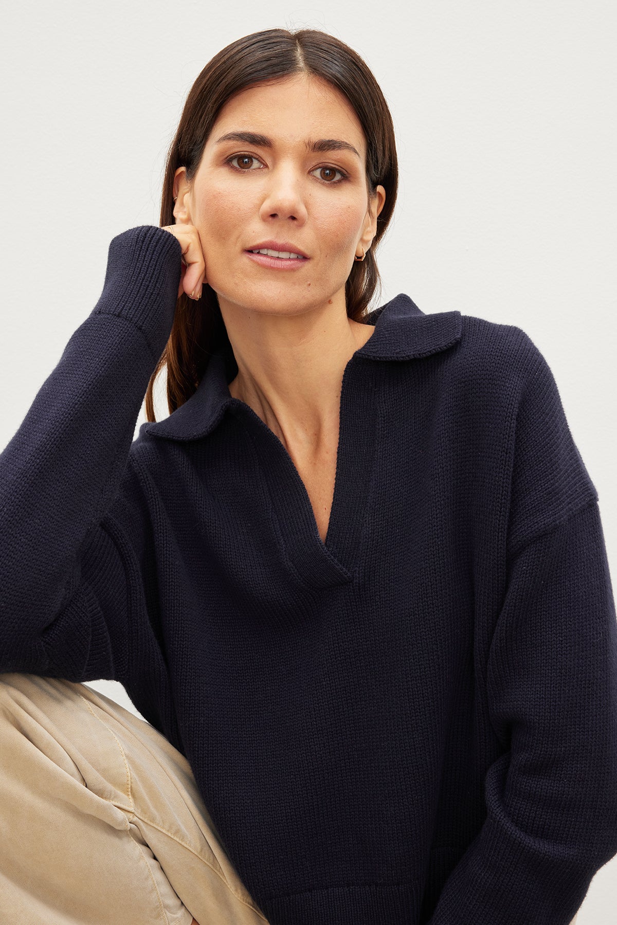 A woman wearing a Velvet by Graham & Spencer LUCIE POLO SWEATER with her hand on her face.-35967604326593