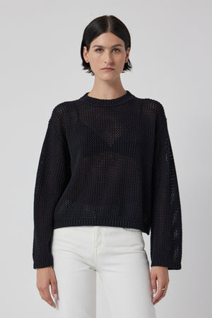 A model wearing a lightweight black KANAN SWEATER by Velvet by Jenny Graham and white jeans.