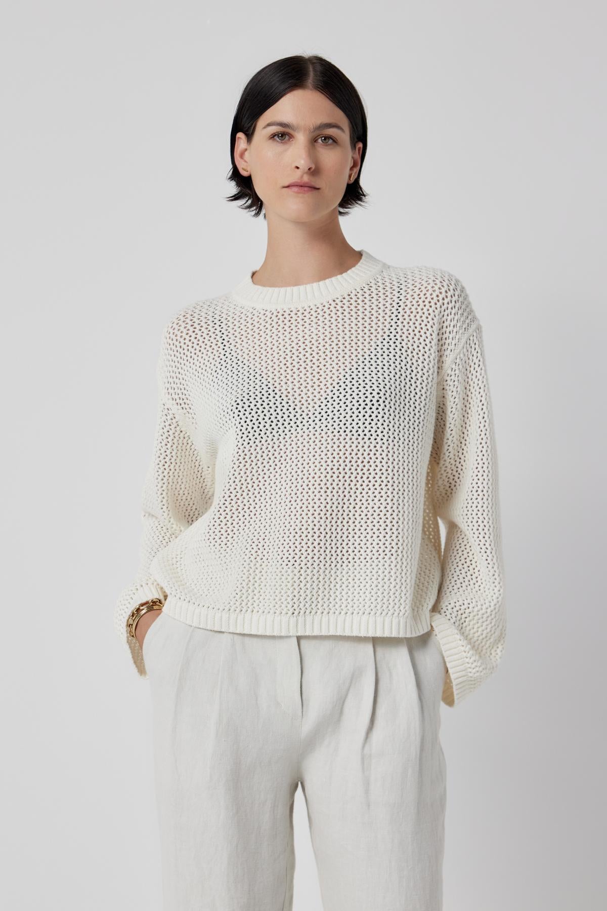   The model is wearing a lightweight KANAN SWEATER by Velvet by Jenny Graham and white trousers. 