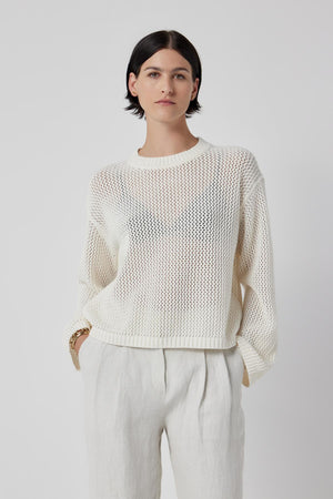 The model is wearing a lightweight KANAN SWEATER by Velvet by Jenny Graham and white trousers.