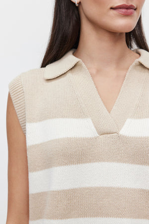 A woman is wearing the MARIETTE SWEATER VEST by Velvet by Graham & Spencer, a knitted sleeveless cotton top featuring beige and white horizontal stripes and a collar, set against a plain background.