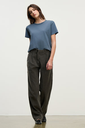A person stands against a plain background wearing a blue short-sleeve t-shirt, Velvet by Graham & Spencer GAIL CORDUROY PANT, and black shoes.