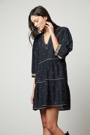 The model is wearing a black Velvet by Graham & Spencer KILEY EMBROIDERED BOHO DRESS with embroidered details.