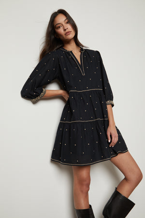 The model is wearing a KILEY EMBROIDERED BOHO DRESS by Velvet by Graham & Spencer with widely spaced gold dots.