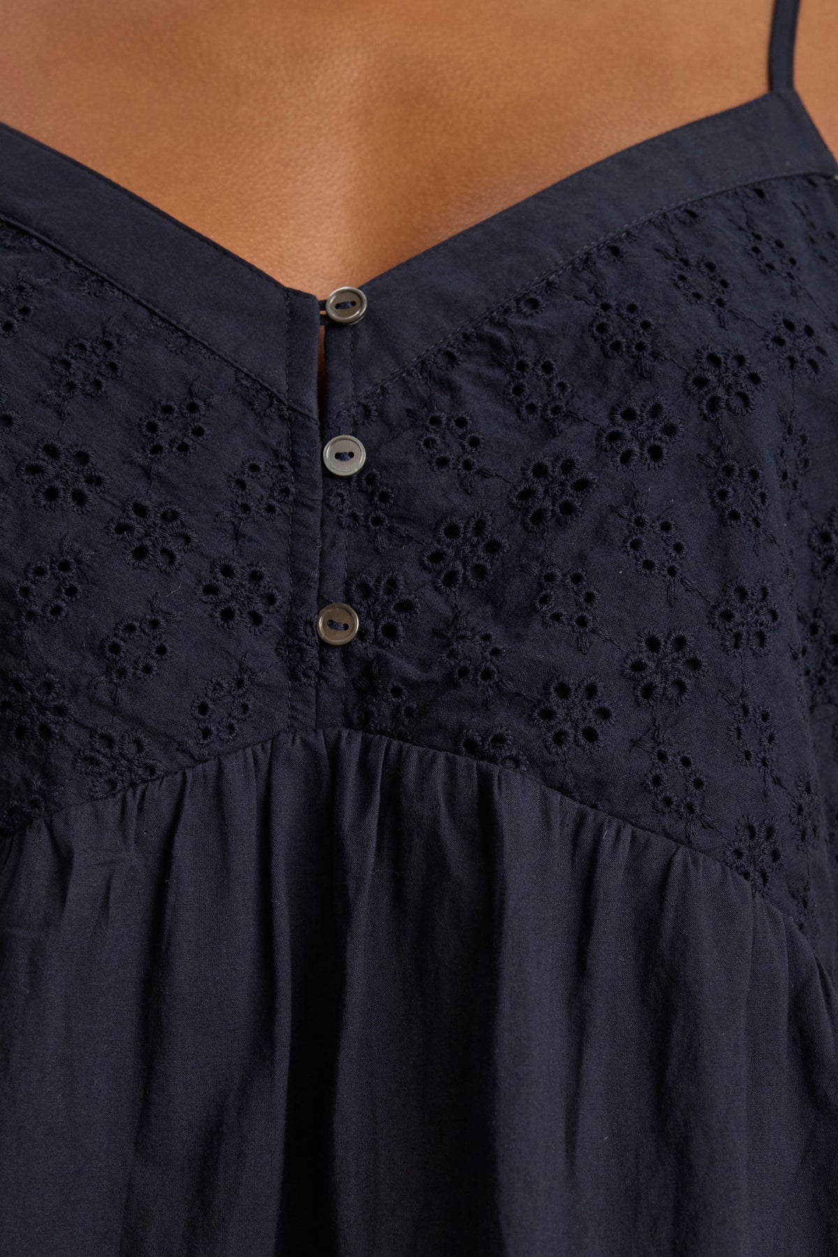 Close-up of the ALIAH EYELET TANK TOP by Velvet by Graham & Spencer in navy cotton poplin, featuring thin straps, floral eyelet embroidery on the bodice, three buttons, and gathered fabric for a soft tiered look.-39123260801217