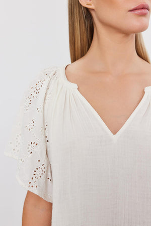 Close-up of a woman wearing a Velvet by Graham & Spencer TISH TOP with embroidered eyelet sleeve details and a v-neckline.