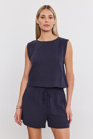 A woman with long hair is wearing a sleeveless navy top and matching Velvet by Graham & Spencer TIBBY COTTON GAUZE SHORT with a drawstring elasticized waist, standing against a plain white background.