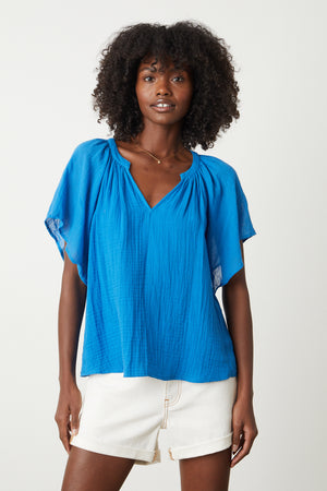a model wearing a Velvet by Graham & Spencer BELLE COTTON GAUZE BLOUSE and white shorts.